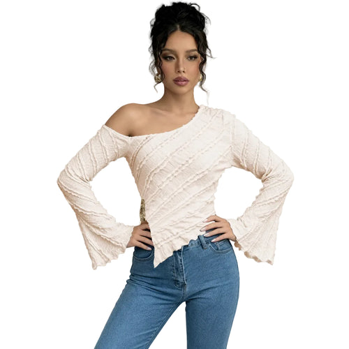 Woman wearing a white off-shoulder top and blue jeans against a gray background