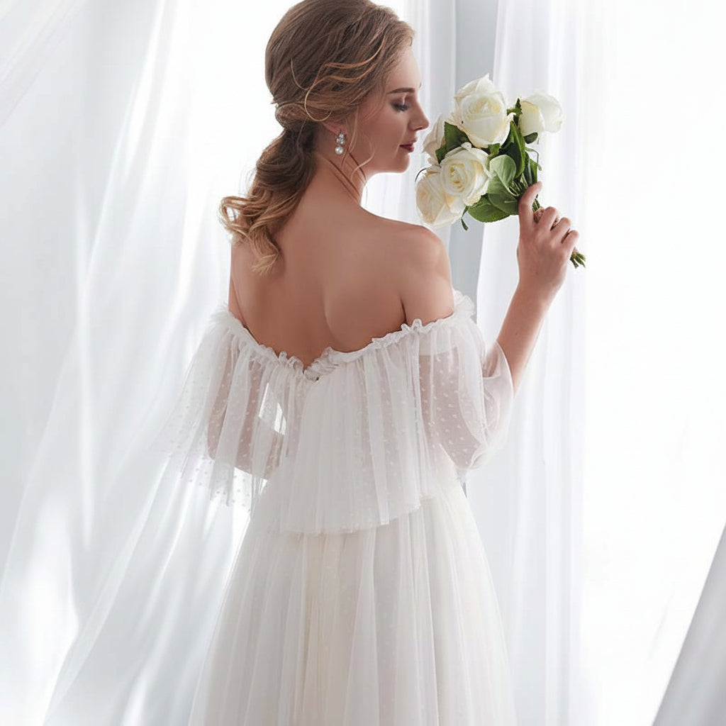 Woman in a white wedding dress holding flowers in a softly lit room.