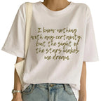 White t-shirt with gold text worn by a person, with a neutral background