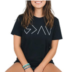 Person wearing a black t-shirt with white geometric design by a lake