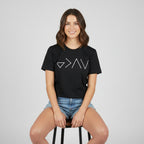 Person wearing a black t-shirt with white geometric design by a lake