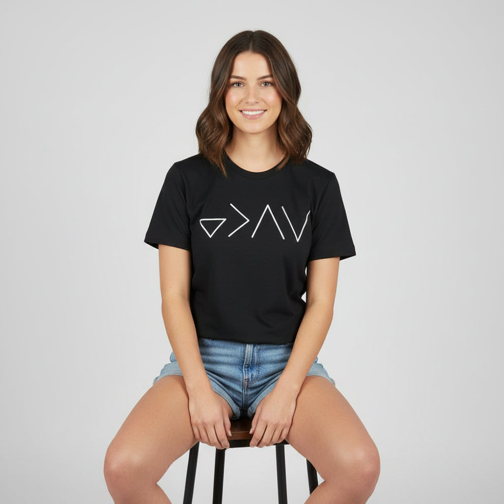 Person wearing a black t-shirt with white geometric design by a lake
