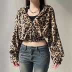 Person wearing a leopard print jacket and jeans against a plain background