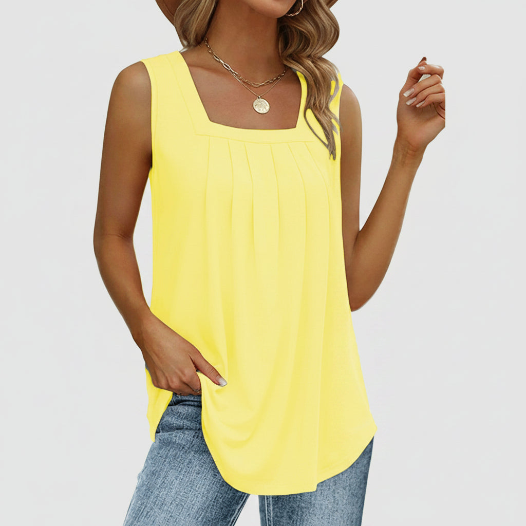 Woman wearing a yellow sleeveless top and blue jeans on a white background