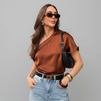 Woman wearing a brown top and sunglasses outdoors