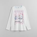 White shirt with pink graphics and text worn by a person, against a neutral background