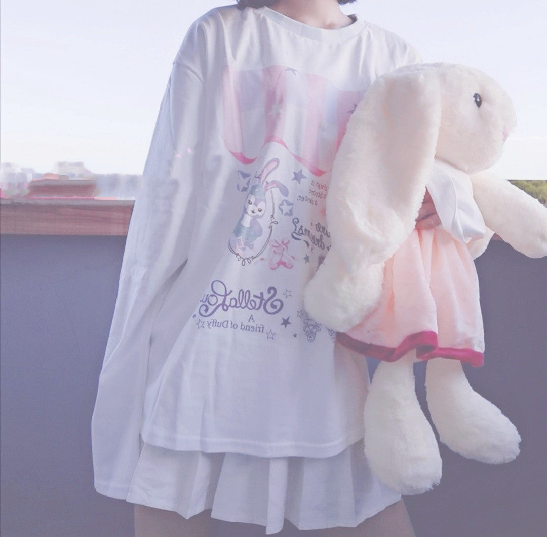 Person wearing a white dress with a cartoon design, holding a plush toy.