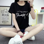 Person wearing a black t-shirt with white text sitting on the floor.