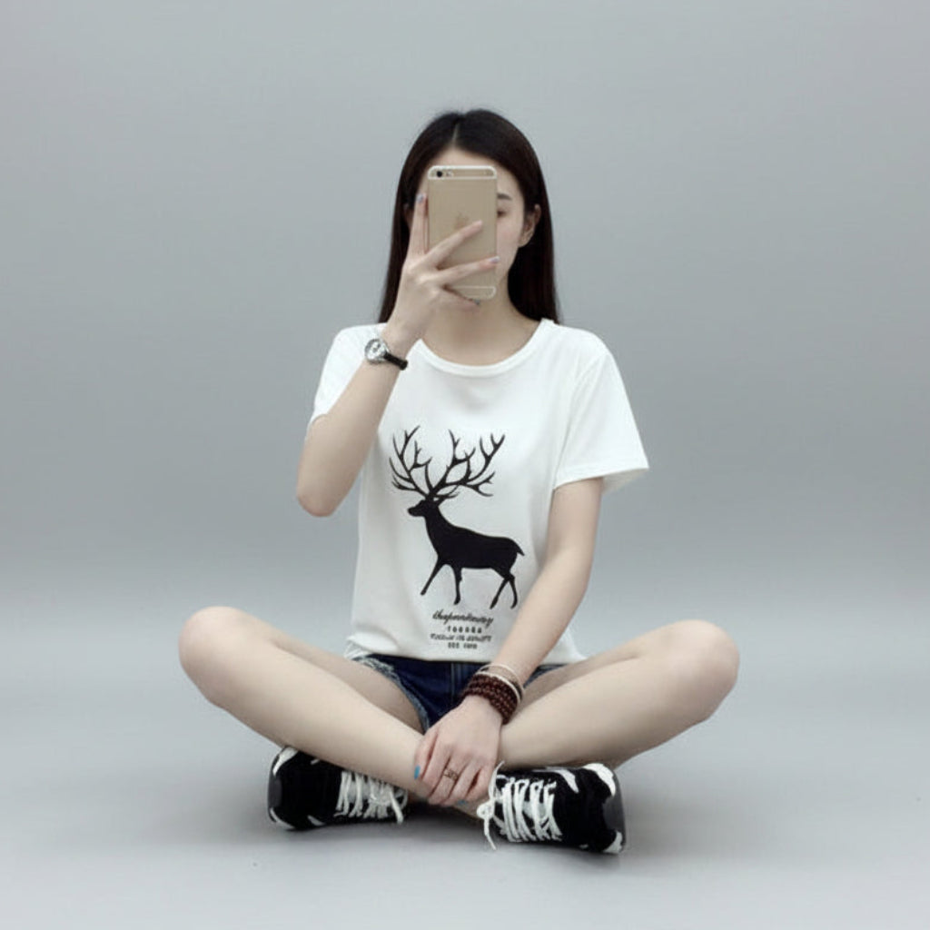Person wearing a white t-shirt with a black deer graphic sitting on the floor.