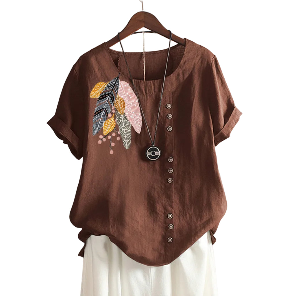 Brown blouse with feather design on a hanger against a beige wall