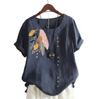 Blue shirt with floral embroidery on a hanger against a beige wall