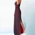 Burgundy strapless gown with a high slit on a light blue background