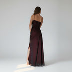 Long dark red evening gown with thin straps and a slit on a white background