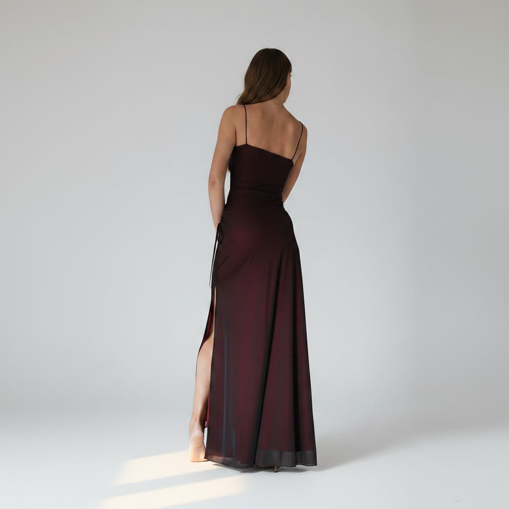 Long dark red evening gown with thin straps and a slit on a white background