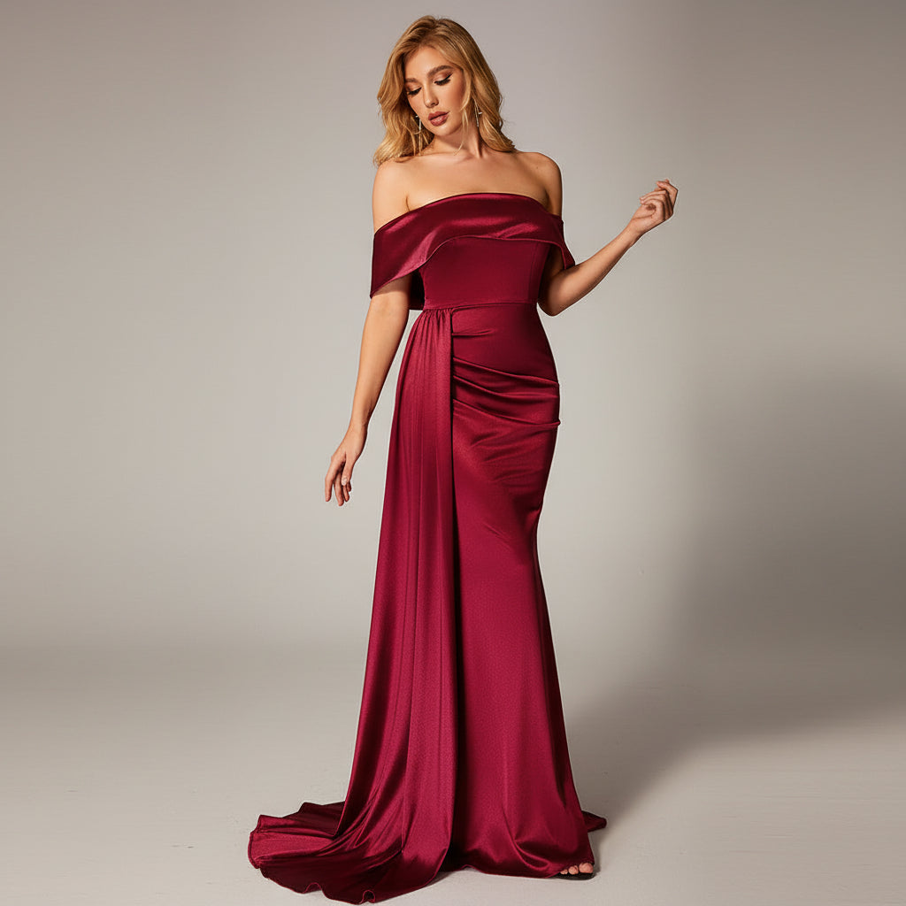 Woman in a burgundy evening gown standing against a dark background with a red couch.