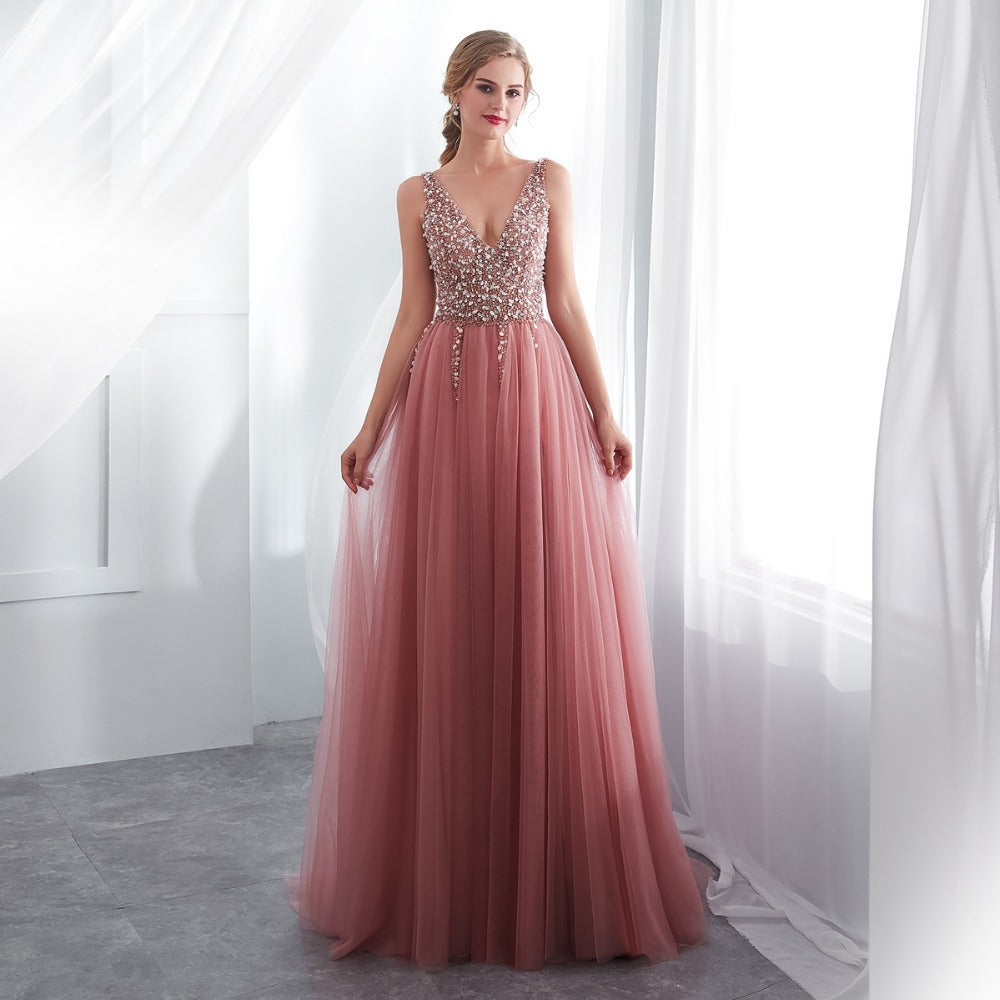 Woman wearing a pink evening gown with a beaded top in a bright room.