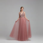 Pink evening gown with beaded top on a model against a white curtain background