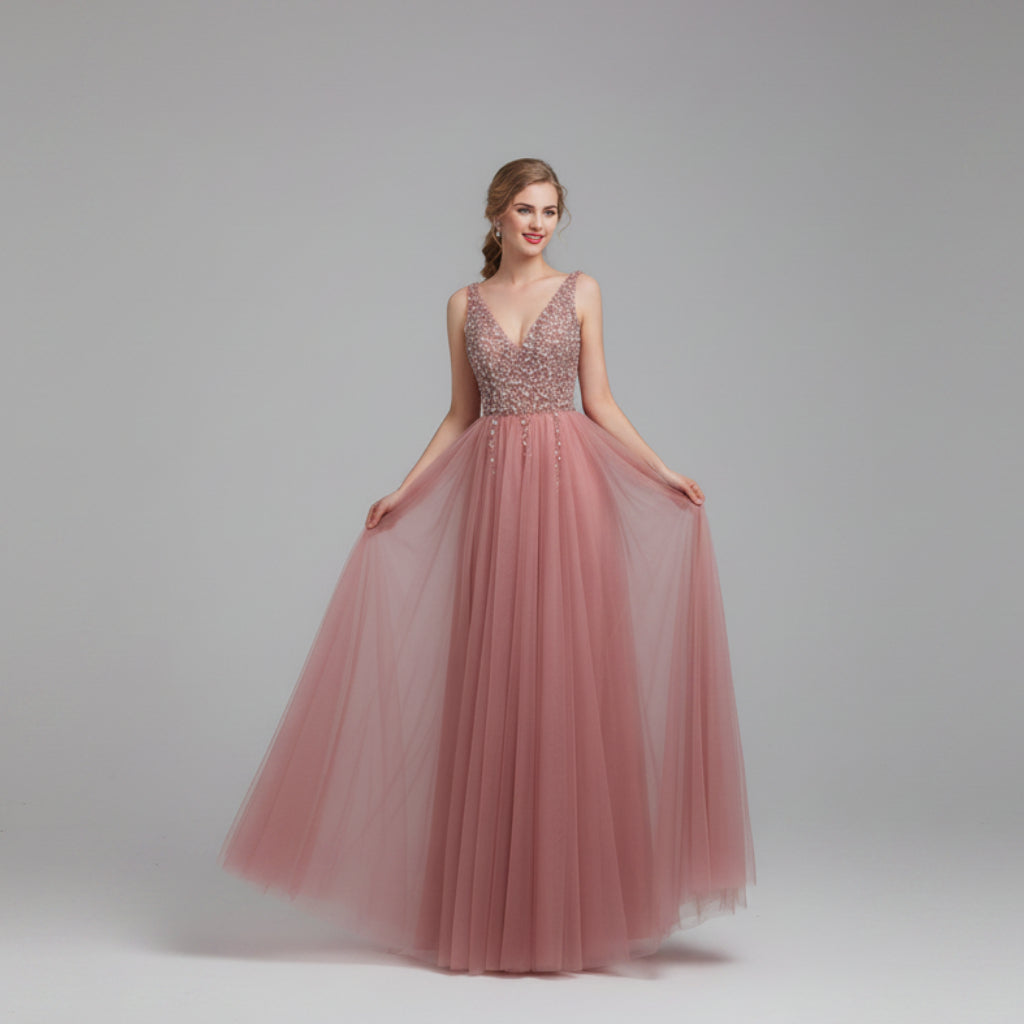 Pink evening gown with beaded top on a model against a white curtain background
